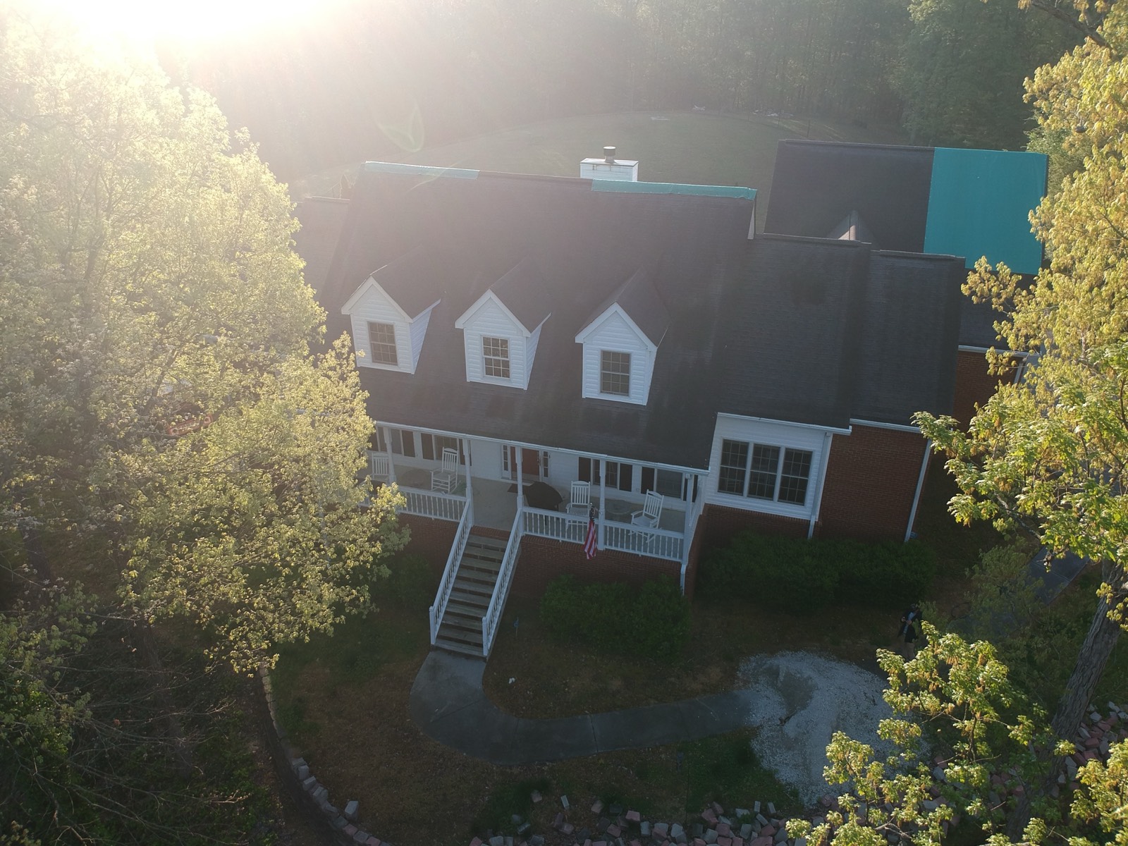 Brick home with three dormers, roof stripped bare before RoofWrap