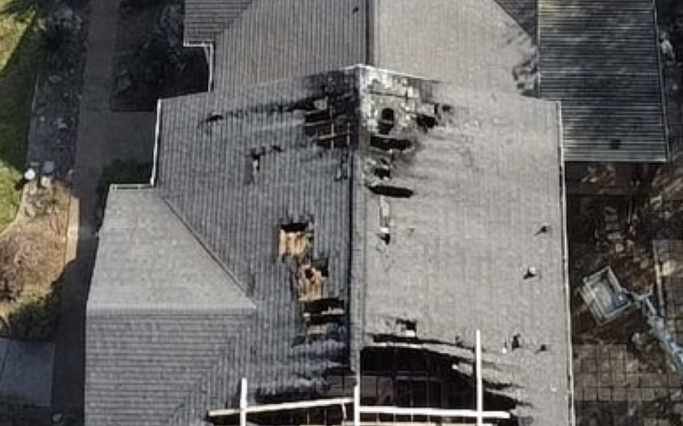 Aerial view of a roof burned open by fire with charred, collapsed decking before RoofWrap
