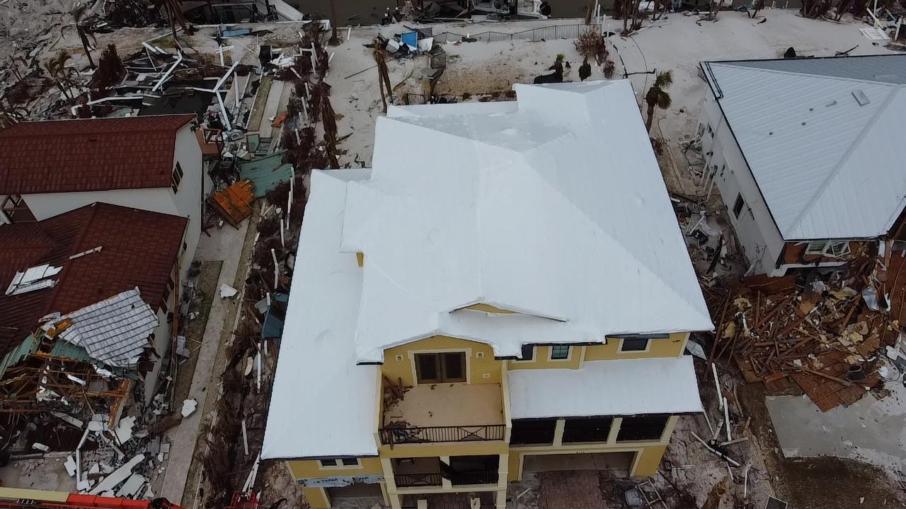 Same hurricane-damaged clay tile home fully sealed under a white RoofWrap membrane