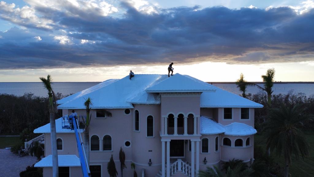Crew finishing a RoofWrap install at dusk on a waterfront estate roof while tile replacement is on order